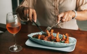 A gourmet dish featuring shrimp served with a glass of rose wine on a dining table.